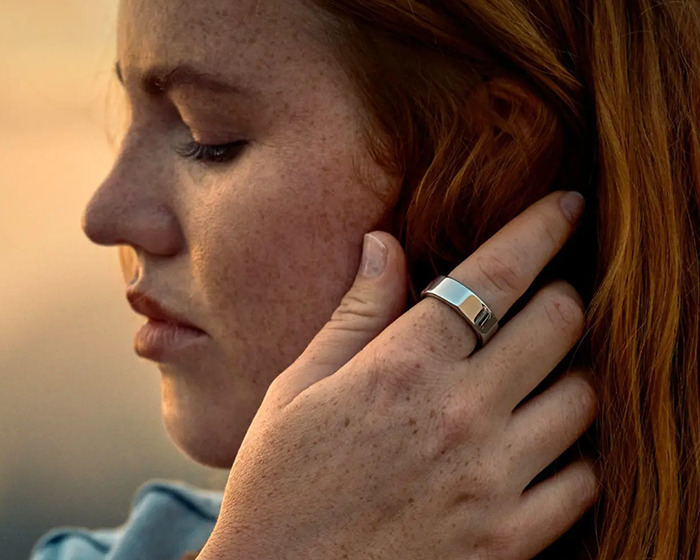 Woman wearing smart ring on finger that detected major illness months before doctor diagnosis in close-up profile view
