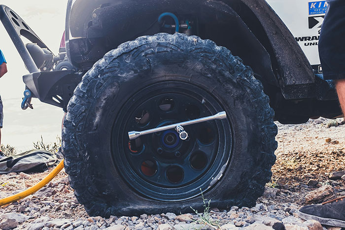 Flat tire on off-road vehicle with wrench attached, illustrating employee misses work due to tire issue.