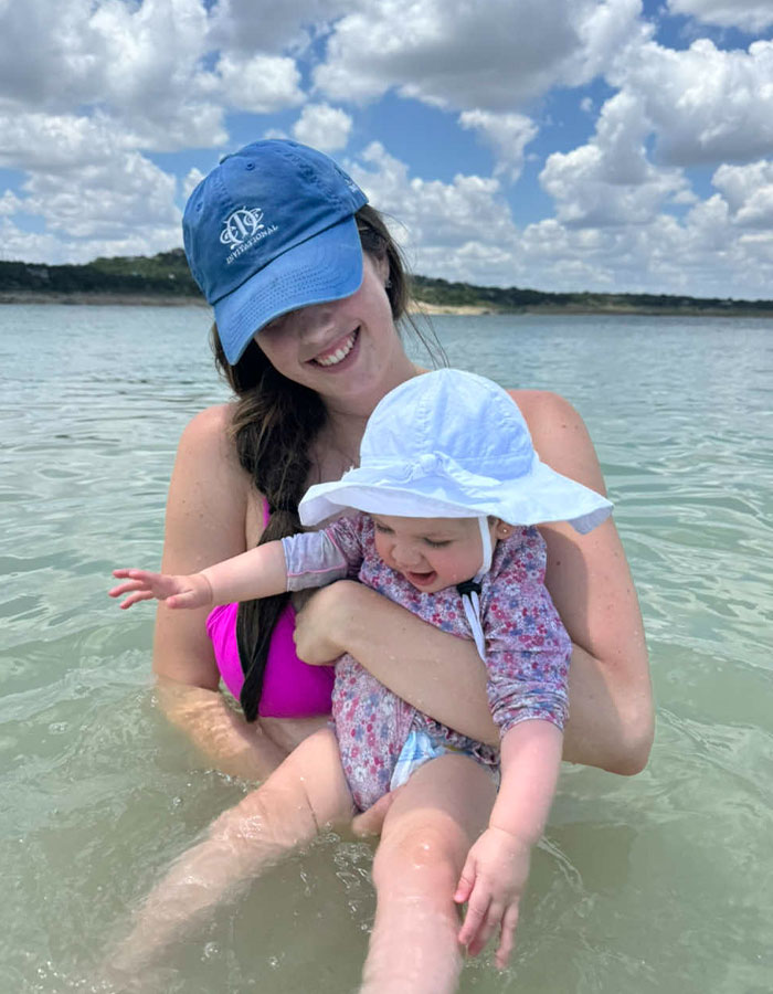 Woman and baby in water outdoors, capturing the honest experience of being a working mom in the U.S. Woman and baby in water outdoors, capturing the honest experience of being a working mom in the U.S.
