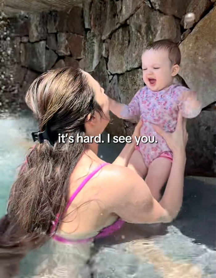 Woman in a pool holding smiling baby, highlighting the challenges of being a working mom in the U.S. Woman in a pool holding smiling baby, highlighting the challenges of being a working mom in the U.S.