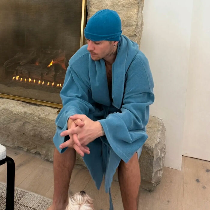 Justin Bieber in a blue robe and hat sitting by the fireplace, reflecting on hidden factors in his troubled marriage. Justin Bieber in a blue robe and hat sitting by the fireplace, reflecting on hidden factors in his troubled marriage.