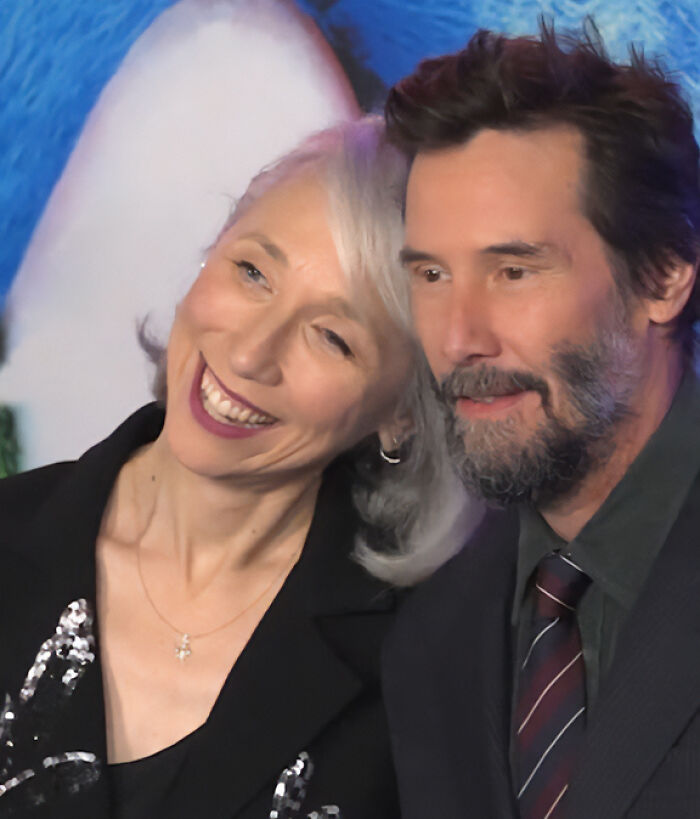 Keanu Reeves and his girlfriend smiling closely together at a public event amid marriage rumors.