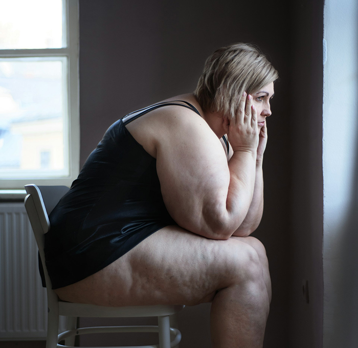 Woman sitting alone on a chair looking out the window, reflecting on a man breaking up after argument about cheese.