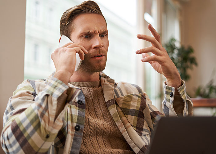Man showing frustration on phone call, illustrating weaponized incompetence in handling simple tasks at home. Man showing frustration on phone call, illustrating weaponized incompetence in handling simple tasks at home.