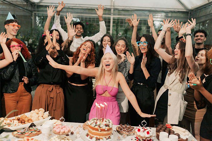 Teen at birthday party surrounded by friends, appearing joyful despite disappointment with parents' gift on her 18th birthday.