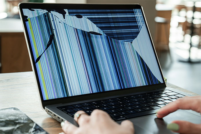 Damaged laptop screen with colorful vertical lines, highlighting kid pouring water on babysitter&rsquo;s laptop after smashing it.