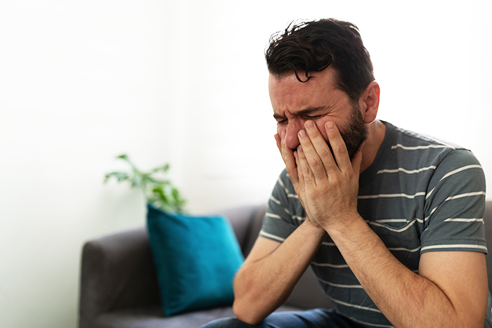 Man covering face with hands, showing distress while sitting on a couch during a widow and single mom date story.