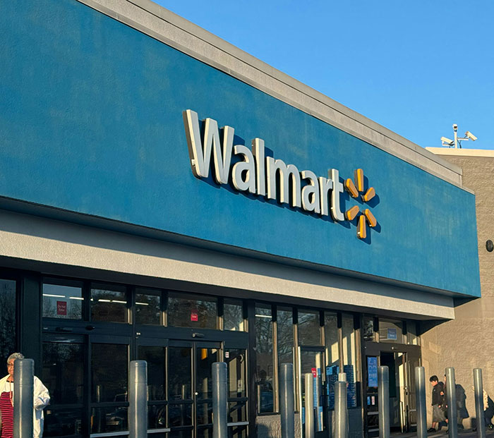 Exterior view of Walmart store entrance with customers near doors relating to angry mob ambush viral video.