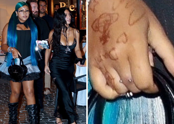 Kim Kardashian with blue hair and black dress, close-up of hand showing dermal piercing on middle finger.