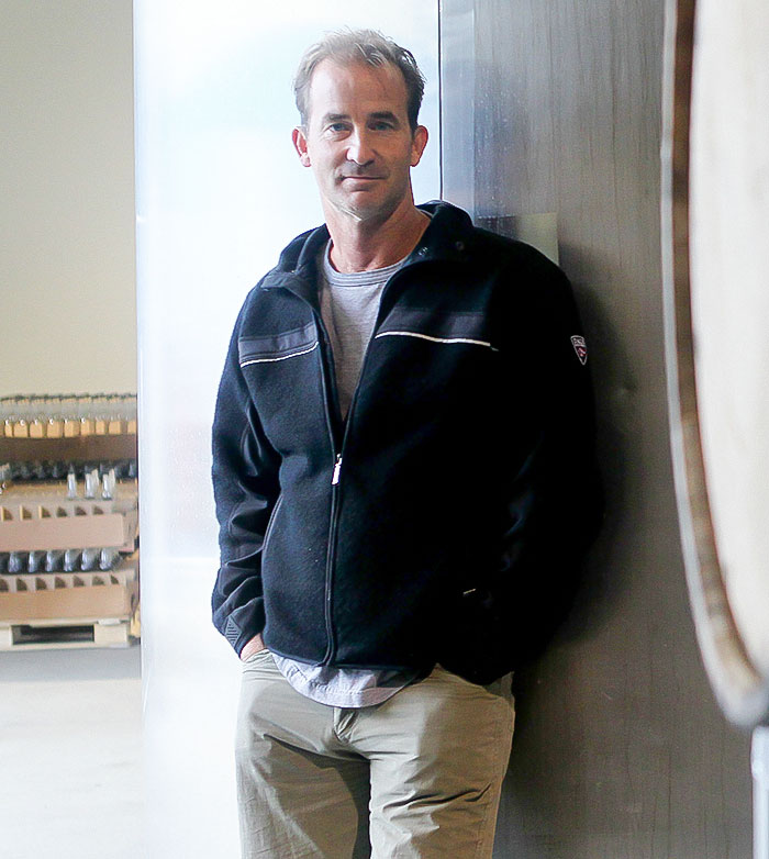 Man leaning against wall indoors, casually dressed, representing husband breaking silence amid divorce news. Man leaning against wall indoors, casually dressed, representing husband breaking silence amid divorce news.