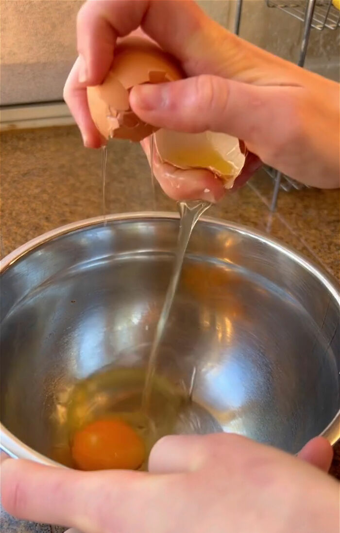 Hands cracking an egg into a stainless steel bowl demonstrating easy tricks to completely change your kitchen game.