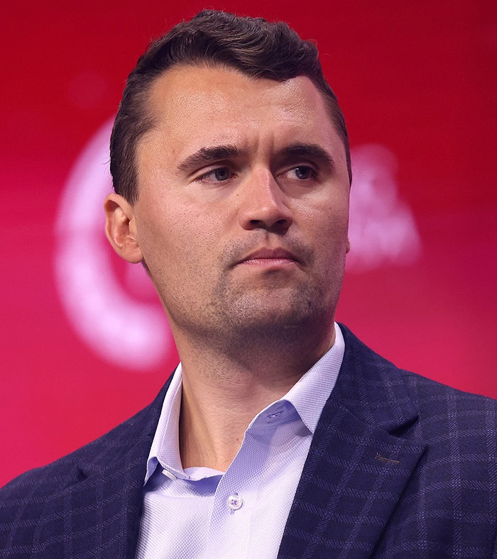 Man in dark blazer and light shirt looking to the side, related to commentator fired after unacceptable Charlie Kirk remarks.