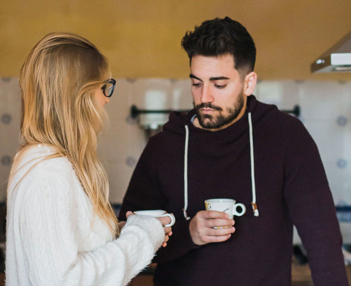 Man and woman having a serious conversation in a kitchen, illustrating unexpected things men didn’t know about women dating.