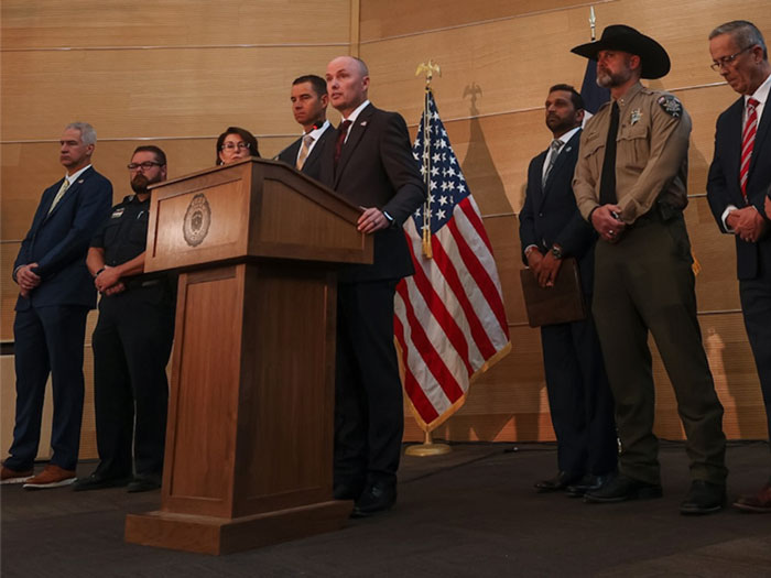 Law enforcement officials and speakers at a podium addressing the Charlie Kirk suspect case and police investigation.