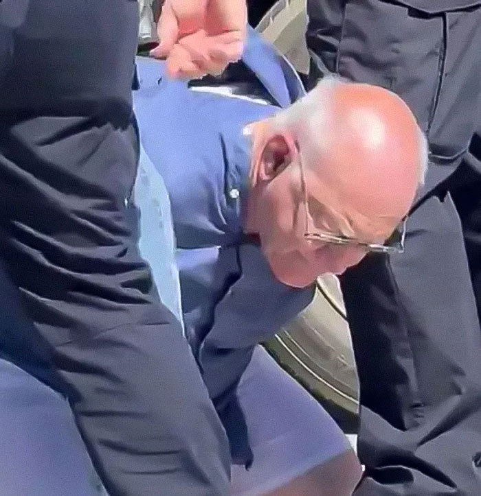 Man in blue shirt handcuffed and surrounded by officers after falsely confessing to Charlie Kirk assassin claim. Man in blue shirt handcuffed and surrounded by officers after falsely confessing to Charlie Kirk assassin claim.