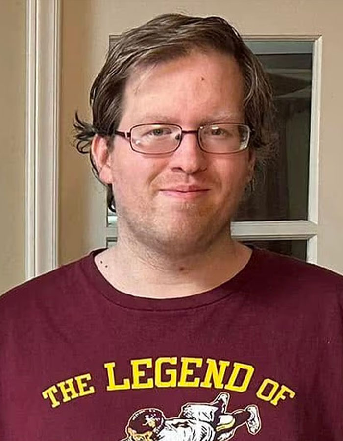Young man wearing glasses and a maroon shirt in a casual indoor setting related to pastor's son accused of disturbing acts.