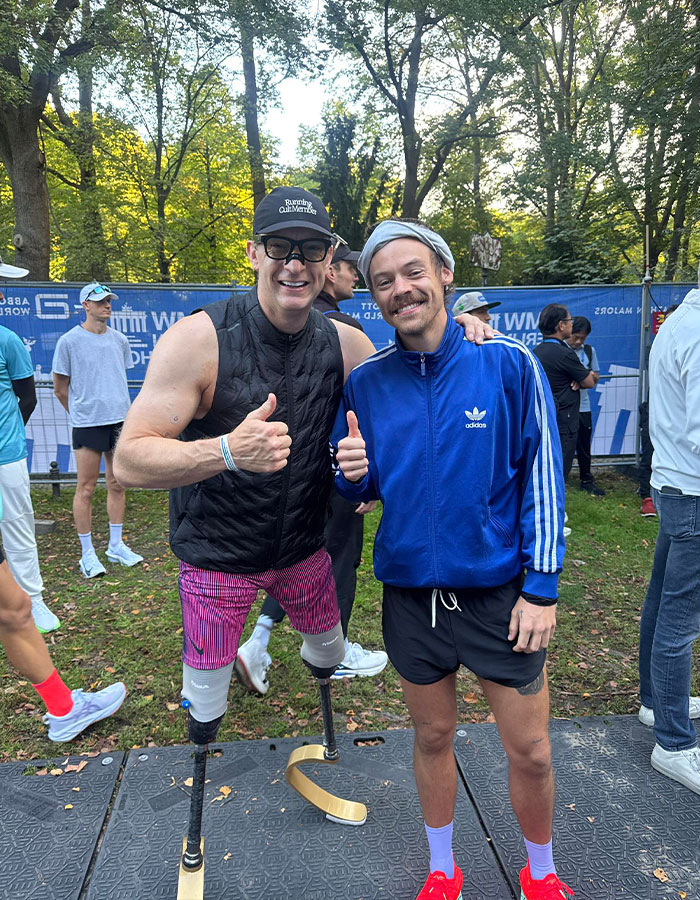 Two men posing outdoors at a marathon event, one with prosthetic running blades showing impressive speed at Berlin Marathon.