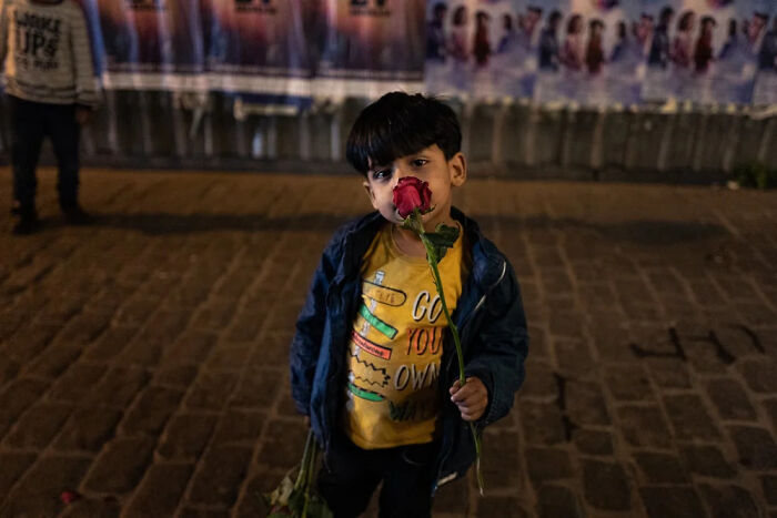 Young child holding a red rose at night, one of the powerful photographs capturing children of the world by Andrea Torrei.