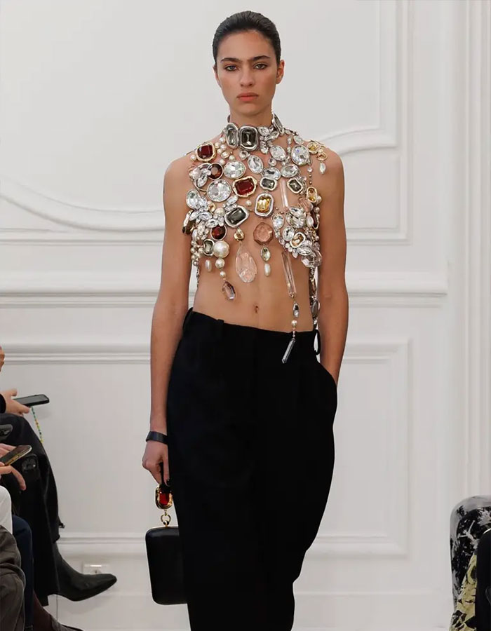 Model wearing an avant-garde embellished top and black pants, highlighting Jenna Ortega&rsquo;s stylist insights on viral Emmy outfit.