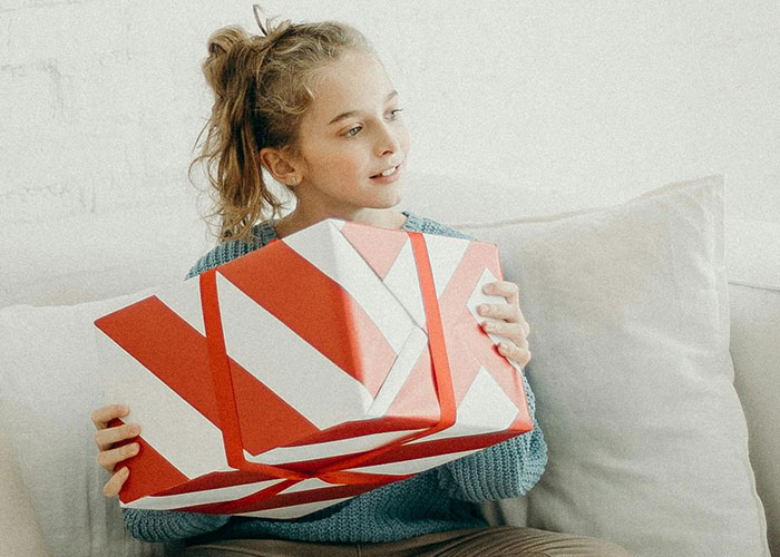 Young girl holding Easter gifts wrapped in red and white paper, reflecting family tensions about keeping daughters in line.