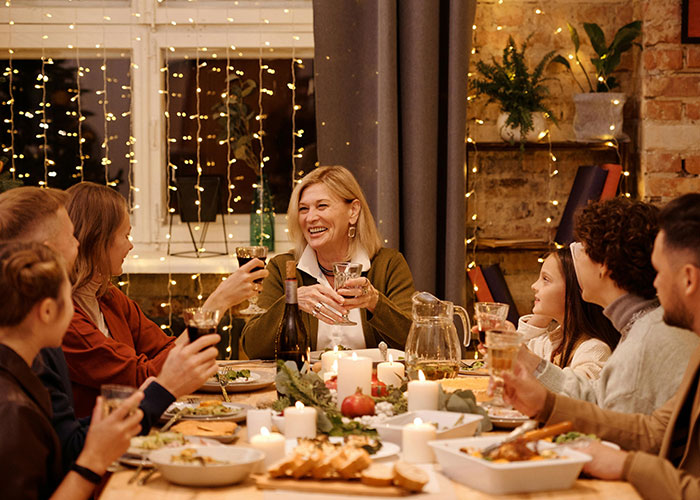 Family gathered at a baby shower, woman smiling and holding a glass while sharing a joyful moment with relatives.
