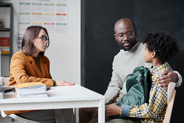 Parent and child meeting with a school official, discussing concerns after school called mom instead of her husband. Parent and child meeting with a school official, discussing concerns after school called mom instead of her husband.