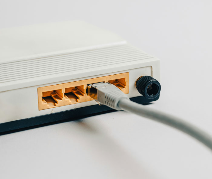Close-up of a network router with an Ethernet cable plugged in, illustrating technology loopholes exploited for savings.