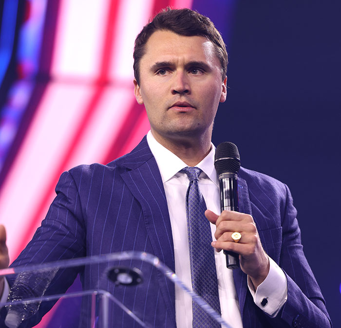 Man speaking at event, wearing blue pinstripe suit and holding microphone, related to Charlie Kirk assassin false confession. Man speaking at event, wearing blue pinstripe suit and holding microphone, related to Charlie Kirk assassin false confession.