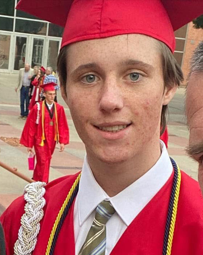 Young person in red graduation cap and gown with tie, related to Tyler Robinson's trans partner disappearance story. Young person in red graduation cap and gown with tie, related to Tyler Robinson's trans partner disappearance story.