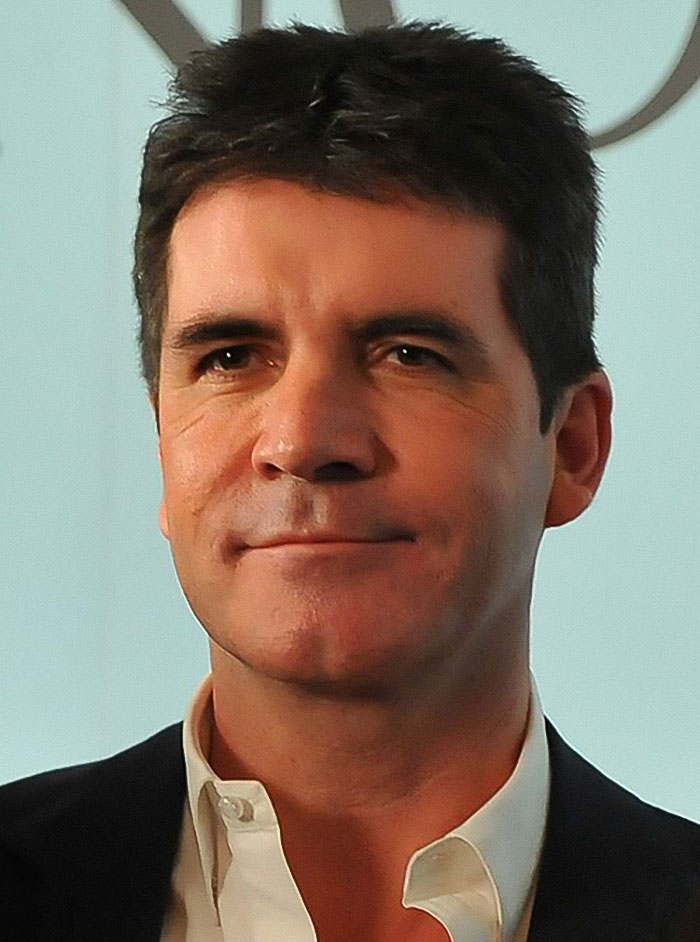 Simon Cowell with a slight smile, dressed formally, viral clip after bike accident raises fan concern.