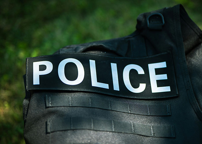 Police tactical vest with police patch resting on grass, related to cop opens fire and self-defense debate.