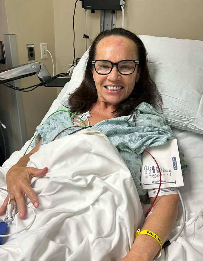 Woman lying in hospital bed wearing glasses and a gown, showing two major symptoms before cancer diagnosis.