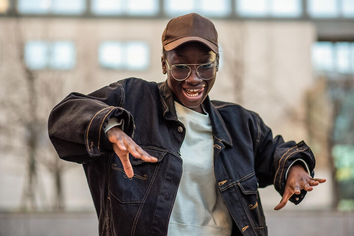 A happy young woman wearing a cap and glasses, expressing excitement about relationship dealbreakers revealed by women.