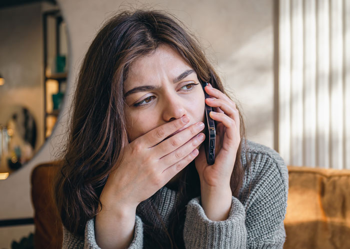 Young woman looking shocked and worried while talking on the phone, capturing emotion linked to affair exposure.