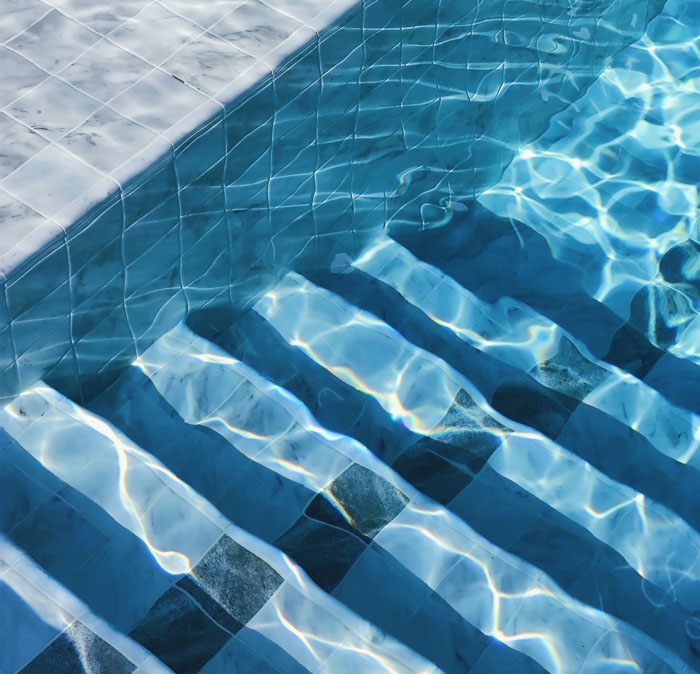 Clear blue water flowing over pool steps with sunlight reflections, symbolizing cops sharing their most horrible experiences.