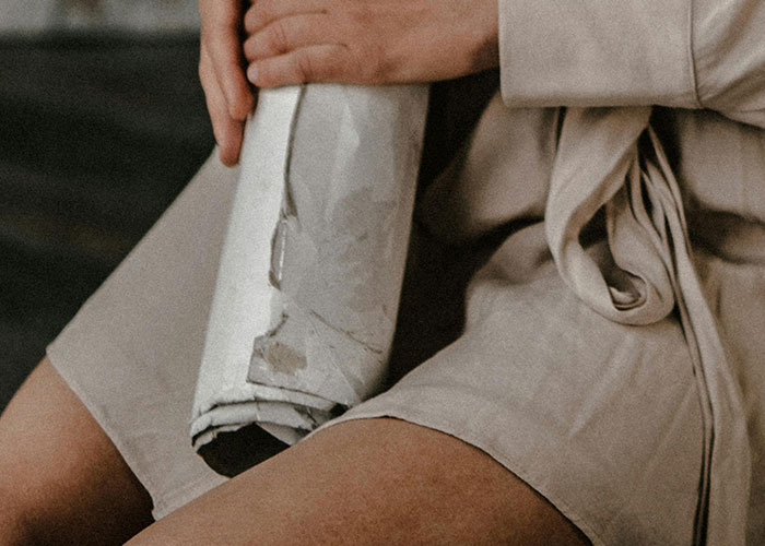 Person in robe sitting and holding a rolled-up paper, representing hidden gems discovered after moving into new homes.