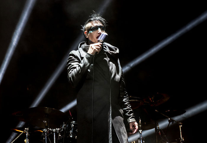 Lead singer with dramatic makeup and dark clothing performs under stage lights at a concert reflecting worst concert experiences.