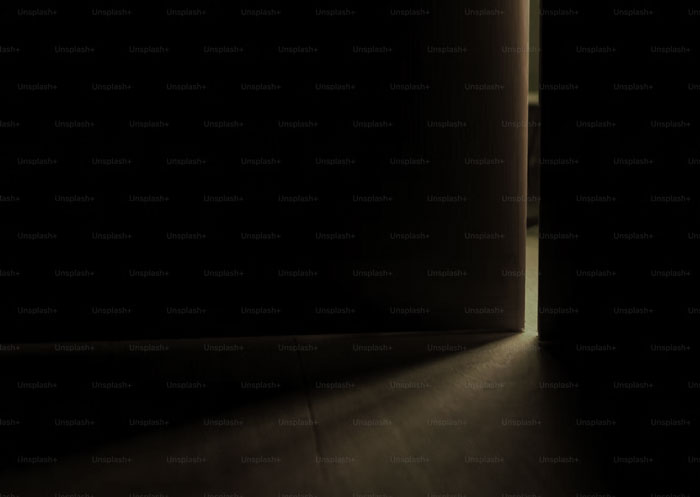 Partially open door casting light into a dark room, evoking a creepy atmosphere while home alone.