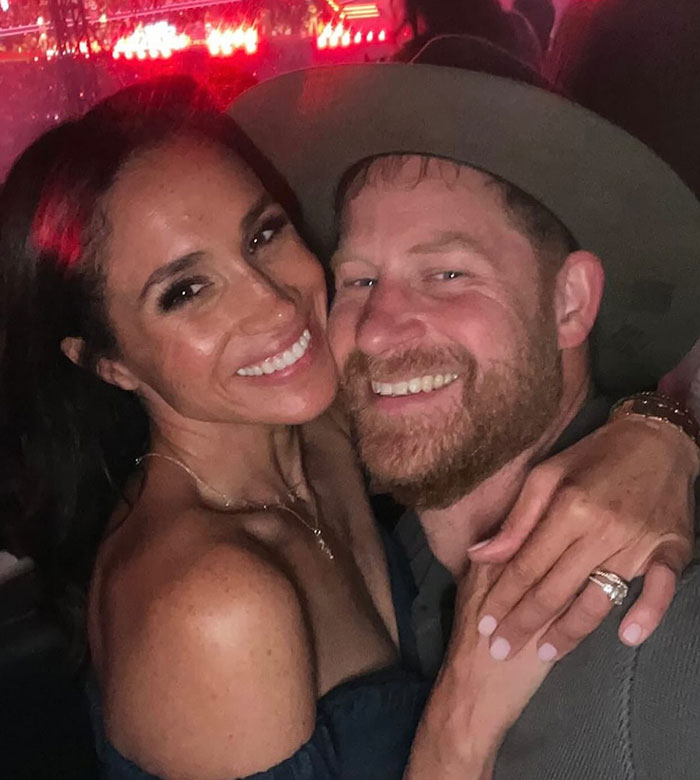 Smiling couple embracing at a party with red lights in the background, related to Meghan Markle reality TV star controversy.