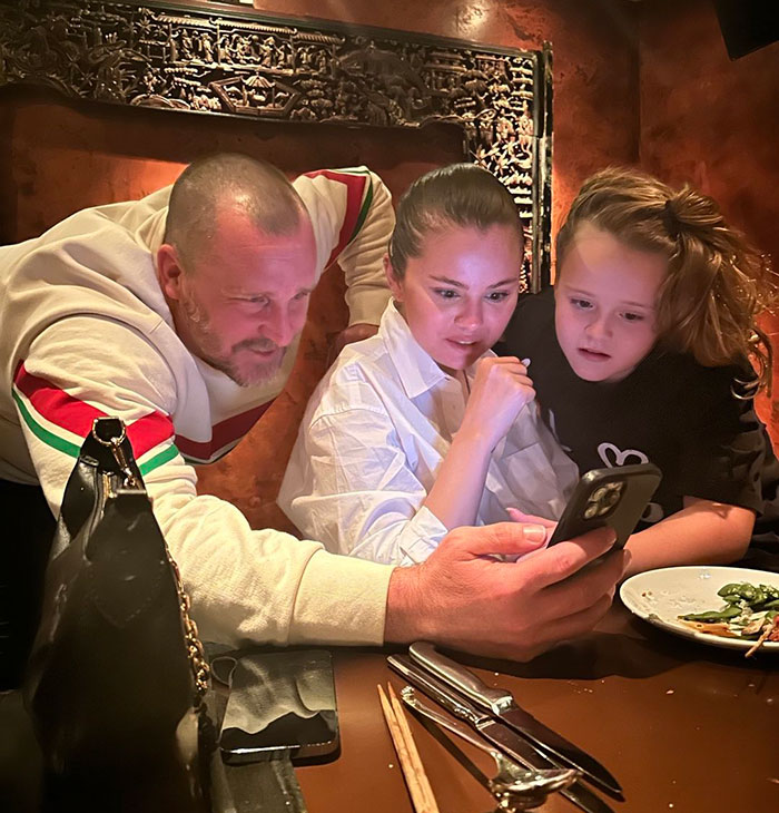 Selena Gomez with family at dinner table looking at phone, related to mom breaking silence on wedding snub controversy. Selena Gomez with family at dinner table looking at phone, related to mom breaking silence on wedding snub controversy.