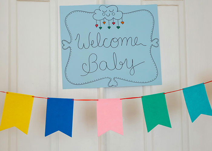 Welcome Baby sign and colorful banners hanging on door for baby shower celebration.