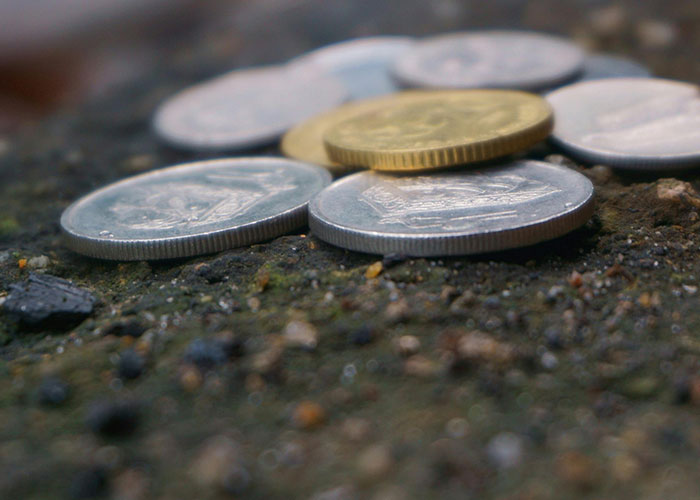Close-up of various coins scattered on a rough surface, illustrating small monetary value in criminal fails context.
