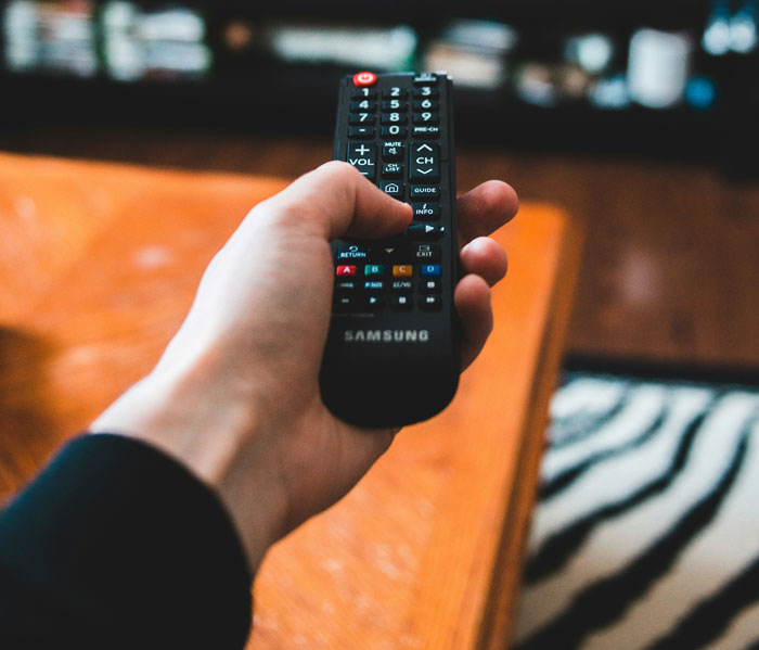 Hand holding a Samsung remote control aimed forward, illustrating brilliant loopholes people exploited with zero regrets.