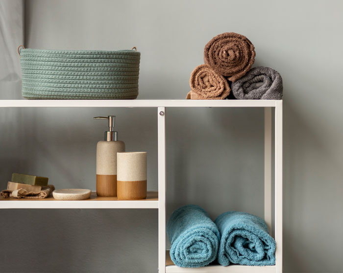 Bathroom shelves with neatly rolled towels and soap dispensers representing unexpected things men didn’t know about women.