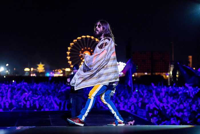 Performer on stage in front of a large concert crowd at night, illustrating the worst concert experiences shared by people.