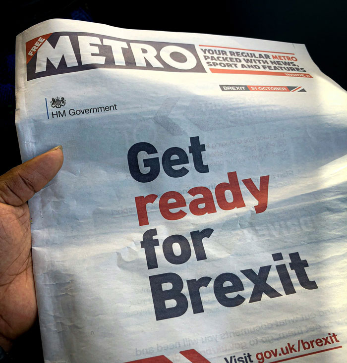 Hand holding a Metro newspaper with bold headline about Brexit, highlighting lack of common sense in groups of people.