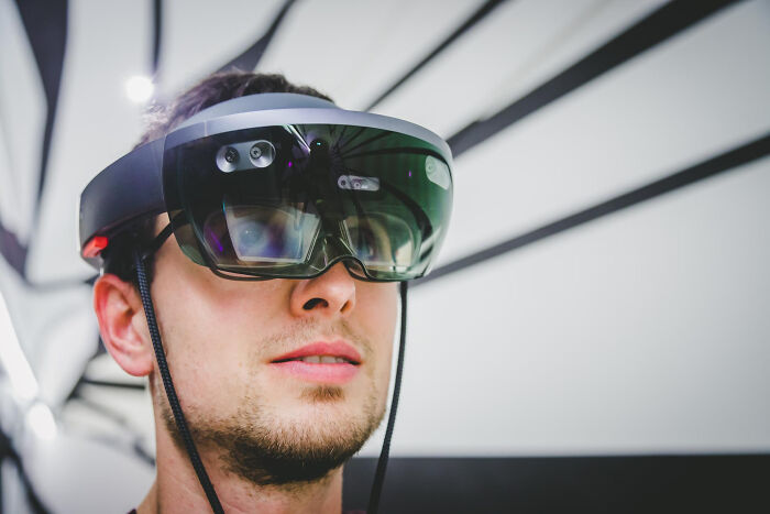 Young man wearing futuristic augmented reality headset testing next big thing technology indoors.