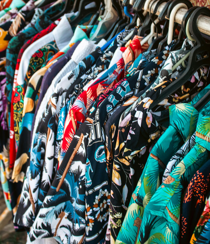 Colorful patterned shirts hanging on black hangers on a wooden rack showcasing fashion loopholes exploited by people.