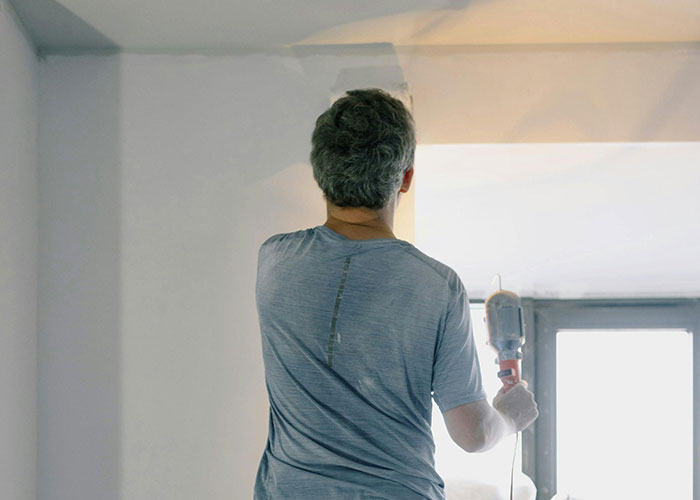 Person painting a wall in their new home, discovering hidden gems during the move-in and renovation process.