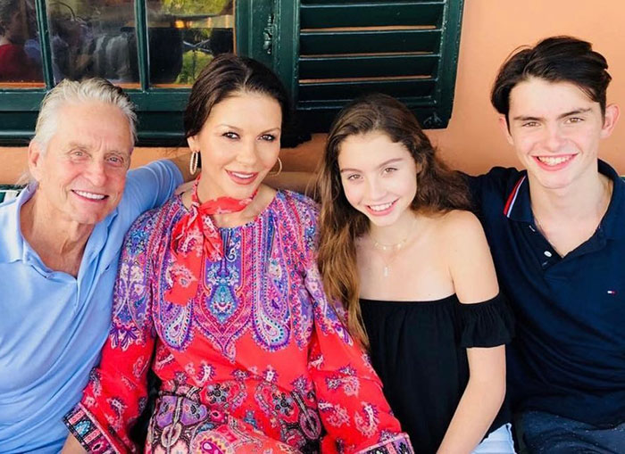 Catherine Zeta-Jones with family members, smiling and seated outdoors, amid controversy over creepy comment about 12-year-old fan